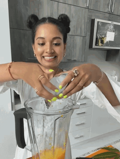 a woman with green nails is making a smoothie in a kitchen with a clock on the wall that says 9:41