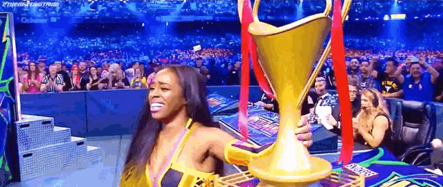 a woman is holding a trophy in front of a crowd of people .