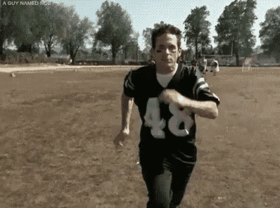 a man in a football uniform is running on a field .