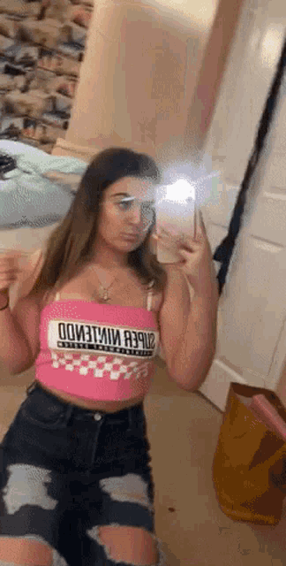 a girl is taking a picture of herself in a mirror while wearing a pink crop top