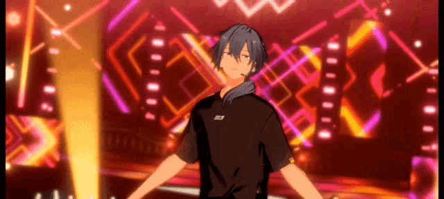 a man in a black shirt is standing on a stage with his arms outstretched in front of a colorful background .