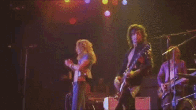 a man playing a guitar on a stage with other people