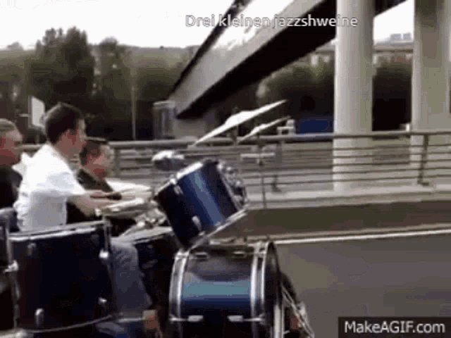 a group of people are playing drums on a bridge .