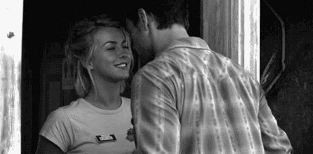 a black and white photo of a man kissing a woman on the forehead .
