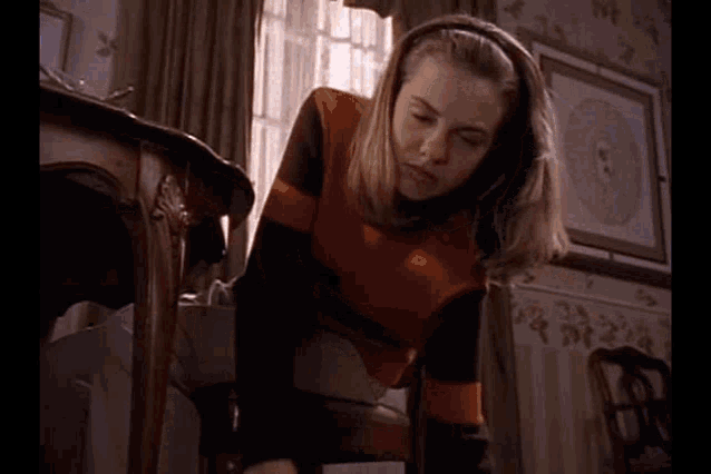 a woman in an orange and black striped sweater is standing in a room