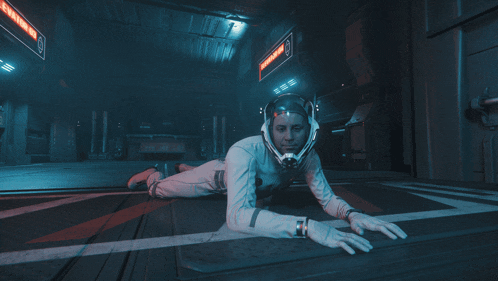 a man in a space suit is laying on the floor in a dark room