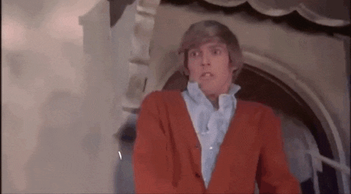 a man in a red jacket is standing in front of a door .