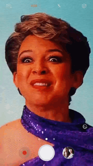 a woman in a purple dress is taking a selfie