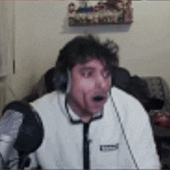 a man wearing headphones is sitting in front of a microphone and making a funny face .