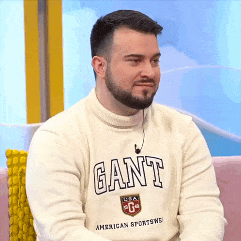 a man wearing a white sweater with the word gant on the front