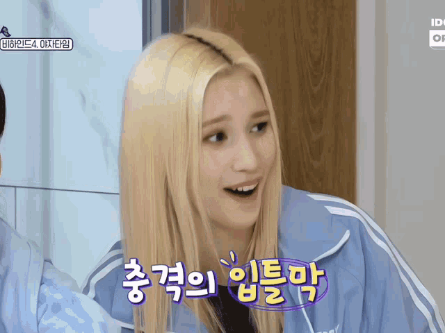 a woman with blonde hair is wearing a blue jacket with white stripes