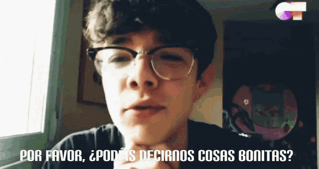 a young man wearing glasses says " por favor " in front of a window