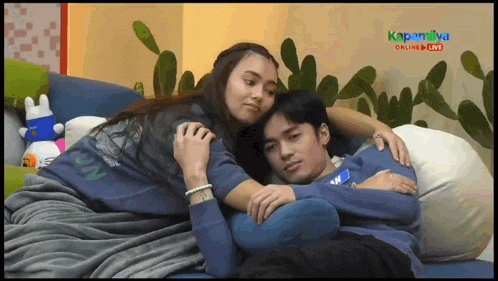 a man and a woman are laying on a couch with kapamilya online live in the background