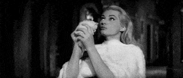 a woman in a white fur coat is holding a small animal in her hands .