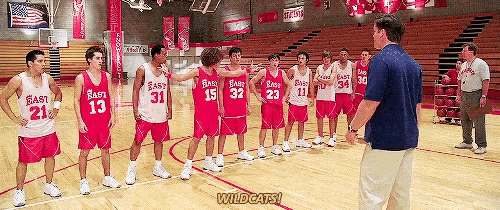 a group of east high school basketball players stand on a court with a coach talking to them