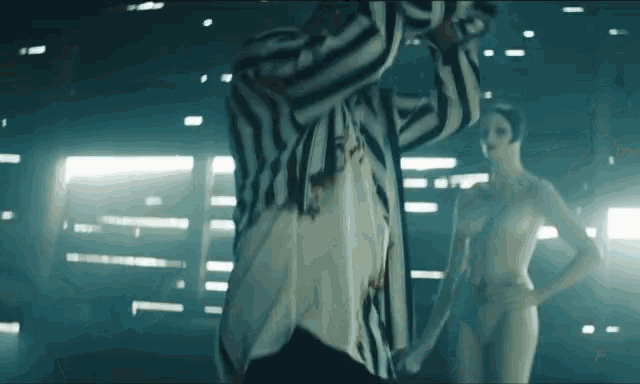 a man in a striped shirt is standing in front of two naked women