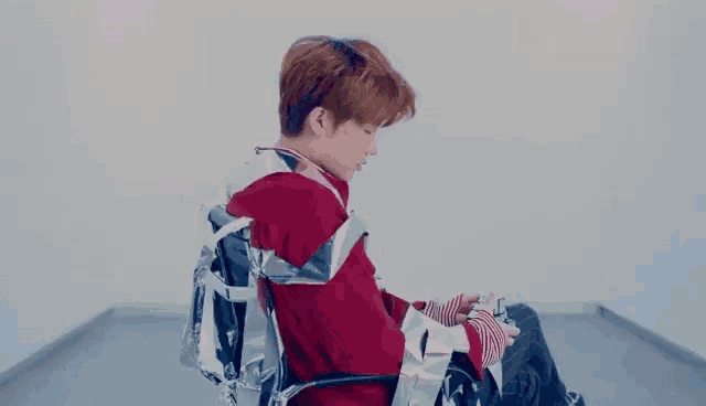 a young man in a red sweater is sitting in a wheelchair wrapped in aluminum foil .