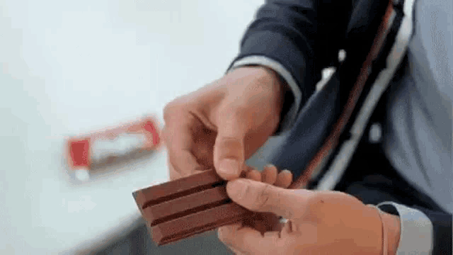 a man in a suit is holding a chocolate bar in his hands .