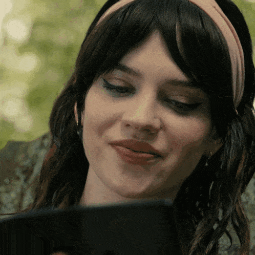 a woman wearing a headband is looking at a cell phone