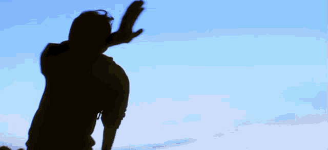 a shadow of a person with their arms outstretched against a blue sky