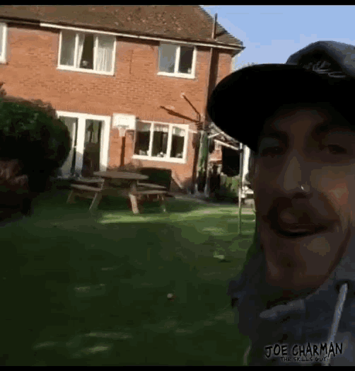a man wearing a nike hat is standing in a backyard