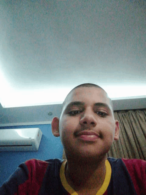 a young man with a shaved head and a mustache is smiling