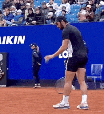 a man is holding a tennis racquet on a court in front of a sign that says " akin "