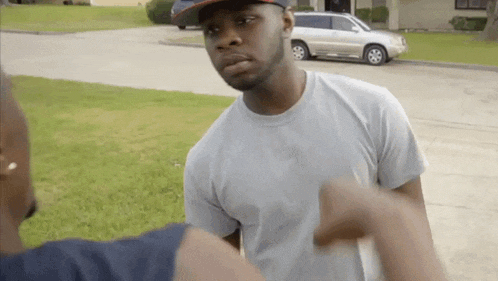 a man in a hat is pointing at another man in a white shirt