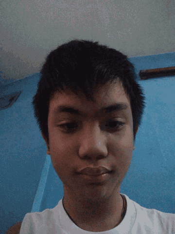 a close up of a man 's face with a blue wall behind him