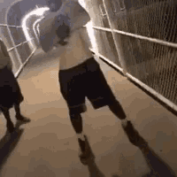 a man in a white shirt is walking down a tunnel .