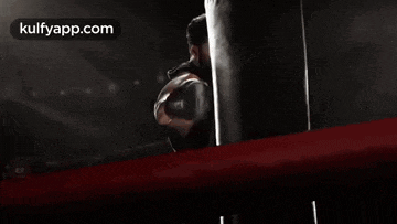 a man in boxing gloves is holding a punching bag .
