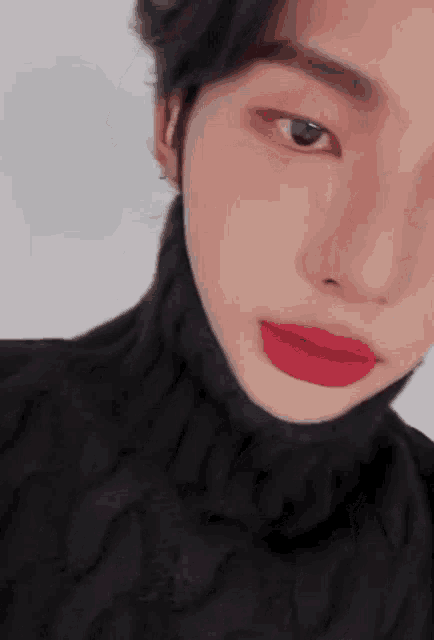 a close up of a person 's face with red lipstick and a black turtleneck .