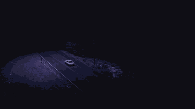 a white car is driving down a dark road