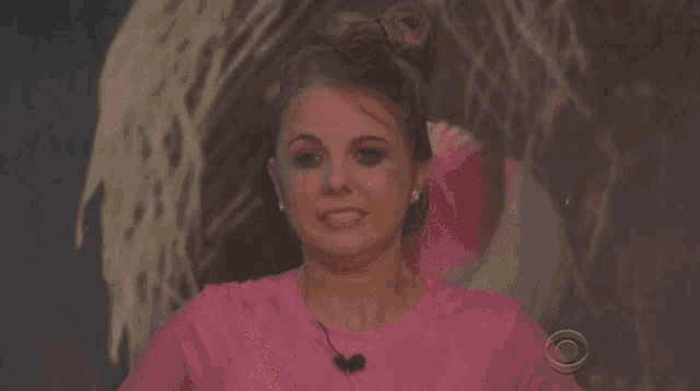 a woman in a pink shirt is making a funny face while wearing a microphone .