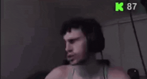 a shirtless man wearing headphones is making a funny face in a dark room .