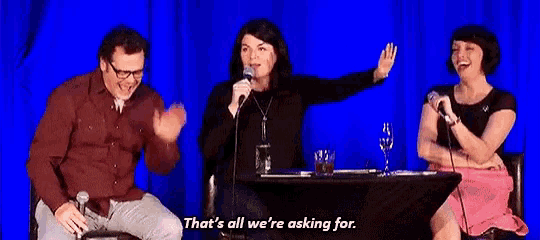 a group of people are sitting at a table with microphones and a woman is holding a microphone .