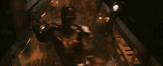 a man in an iron man suit is fighting another man in a dark room .