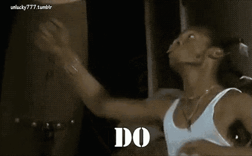 a man in a white tank top is dancing with his arms outstretched and the words `` do '' written on the screen .