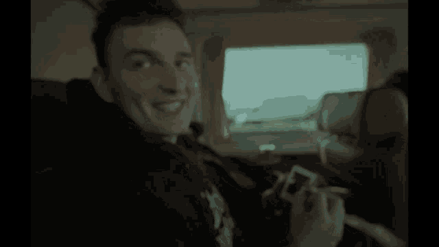 a man is sitting in a car with a hoodie that says ' a ' on it