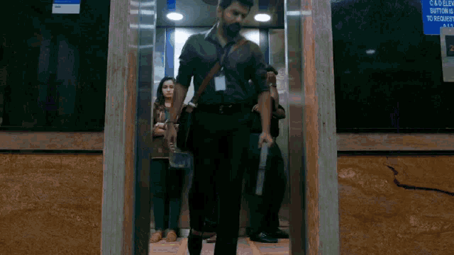 a man walking out of an elevator with a sign on the wall that says c & d elev button is to request