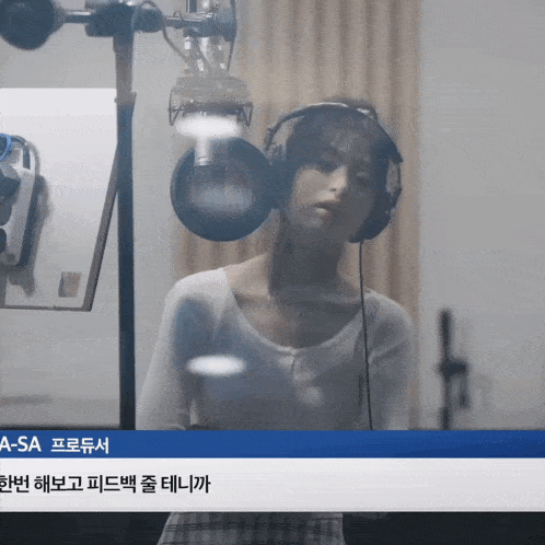 a woman wearing headphones is standing in front of a microphone and a sign that says a - sa