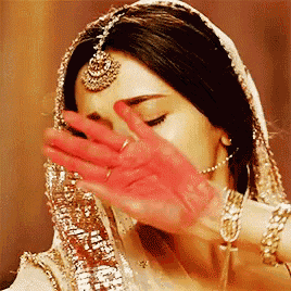 a woman is covering her face with her hand while wearing a veil .
