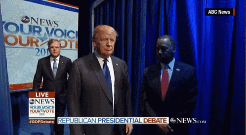 a man in a suit and tie is standing in front of a blue curtain that says abc news