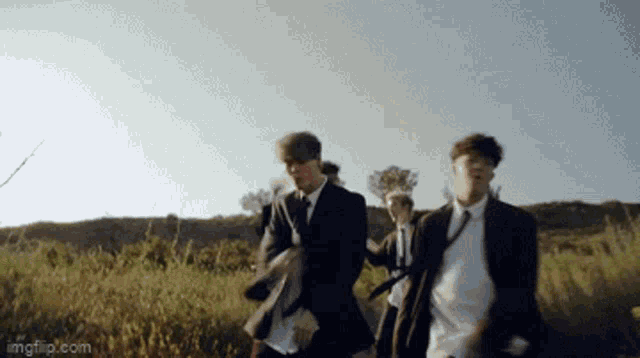 a group of men in suits and ties are walking in a field ..