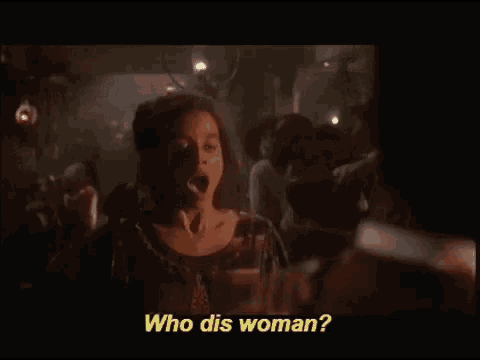 a woman is talking to a man in a dark room and the words who dis woman are visible .