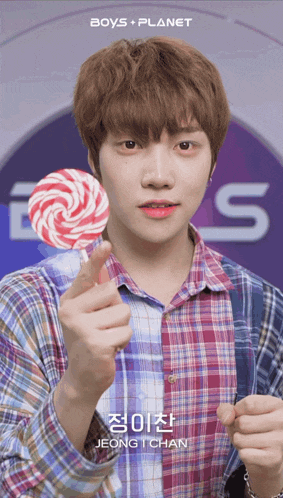 a young man holding a lollipop in front of a boys planet sign
