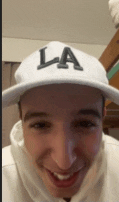 a young man wearing a white la hat is smiling .