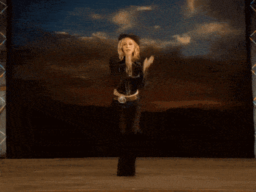a woman wearing a cowboy hat and chaps is dancing