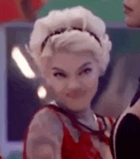 a woman with white hair is wearing a headband and a red dress .