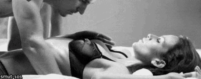 a black and white photo of a man touching a woman 's breasts .
